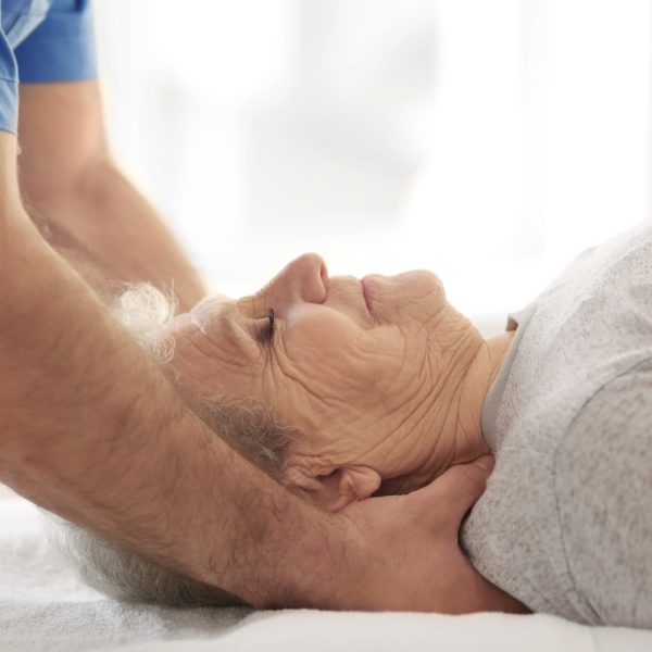 Physiotherapist working with elderly patient in clinic, closeup
